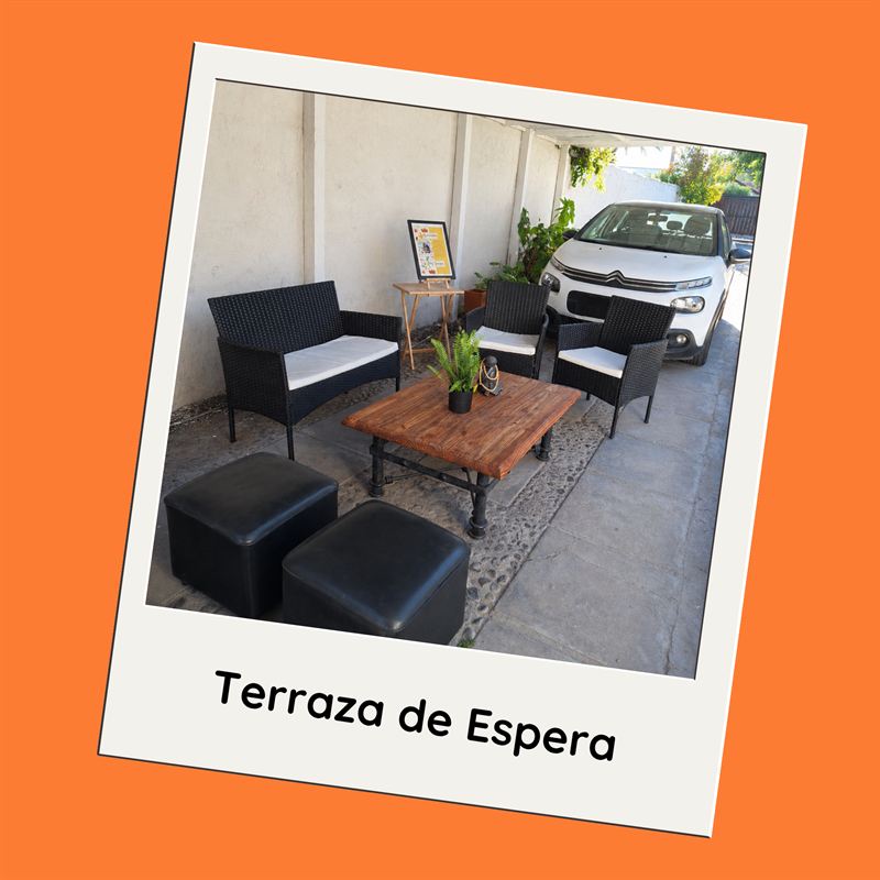 Terraza de espera: sillones de mimbre y mesa de centro de madera, en un patio techado.
